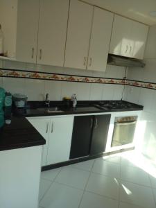 eine Küche mit weißen Schränken und schwarzen Arbeitsplatten in der Unterkunft Paz e sossego, 15 minutos da lagoa in Iguaba Grande