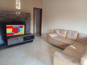 ein Wohnzimmer mit einem Sofa und einem Flachbild-TV in der Unterkunft Paz e sossego, 15 minutos da lagoa in Iguaba Grande