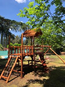 un parque infantil de madera con un tobogán en un parque en EZEIZA quinta cedro azul 10 min del aeropuerto en Ezeiza