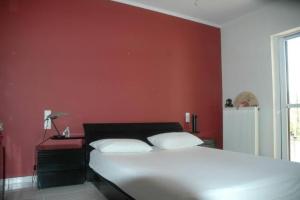 - une chambre avec un lit blanc et un mur rouge dans l'établissement ellie, à Patras