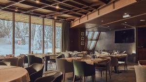 uma sala de jantar com mesas, cadeiras e janelas em Grey Hotel Kopaonik em Kopaonik