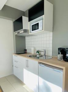 a kitchen with a sink and a microwave at Aramis Studio Hotel in Luxembourg