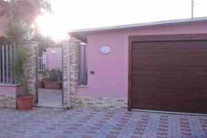een roze huis met een bruine garagedeur bij Villa Salvo in Balestrate