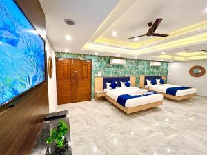 a bedroom with two beds and a flat screen tv at The Eleganza in Jhājra