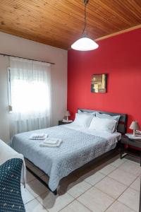 Un dormitorio con una pared roja y una cama grande en Cottage Lina, en Édessa