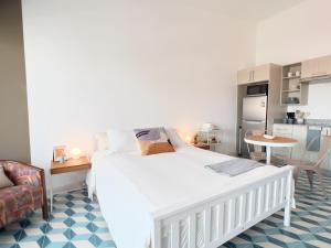 a bedroom with a white bed and a kitchen at Maison Boheme - La Manzana Panama in Panama City