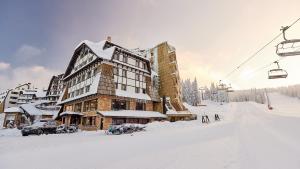 eine Skihütte im Schnee neben einem Skilift in der Unterkunft Grey Hotel Kopaonik in Kopaonik