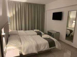 a hotel room with two beds and a mirror at La Veranda Hotel in Larnaca