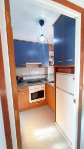 una cocina con armarios azules y un aparato blanco en Anchoveta, en Calonge