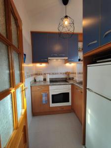 cocina con armarios azules y nevera blanca en Anchoveta, en Calonge