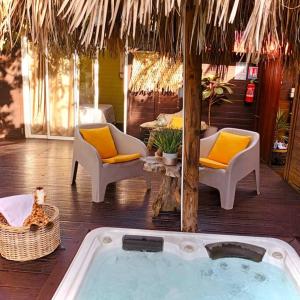 uma banheira de hidromassagem num resort com cadeiras e uma mesa em Cabane Charme & Jacuzzi em La Plaine