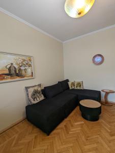 ein Wohnzimmer mit einem schwarzen Sofa und einem Tisch in der Unterkunft Scanderbeg Square Apartment in Tirana