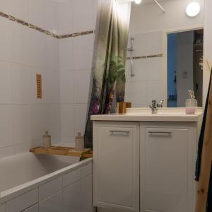 een witte badkamer met een bad, een wastafel en een bad tubermott bij Appartement cosy in Sarlat-la-Canéda