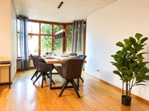 a dining room with a table and chairs and a plant at Relax & Business Apartment 122qm mit Balkon, Kamin und Disney+ in Sindelfingen
