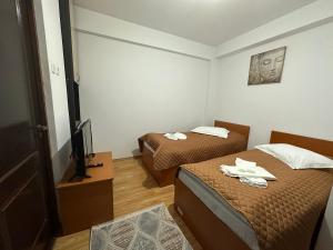 Habitación pequeña con 2 camas y TV. en Casa Rustic cazare, en Piteşti