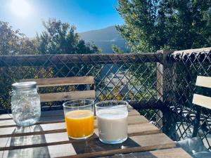 dos vasos de leche y zumo de naranja en una mesa de madera en Terraza de Poqueira, en Capileira