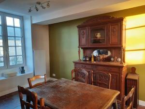 ein Esszimmer mit einem Tisch und einem Holzschrank in der Unterkunft Gîte du Manoir in Subles