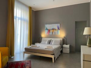een slaapkamer met een bed en een schilderij aan de muur bij Il Teatrino del Bonajuto in Caltagirone