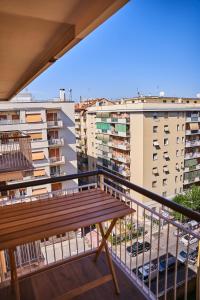 - un balcon avec un banc en bois et des bâtiments dans l'établissement Tramonto su Roma [ SELF CHECK-IN METRO A ], à Rome