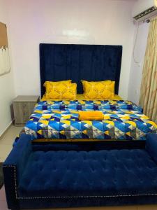 uma grande cama azul com uma cabeceira azul e almofadas amarelas em Jesam House em Suru Lere