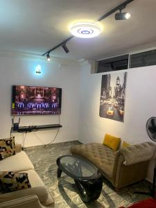 uma sala de estar com um sofá e uma televisão de ecrã plano em Jesam House em Suru Lere
