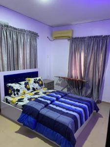 Schlafzimmer mit einem Bett mit blauer Decke in der Unterkunft Jesam House in Suru Lere