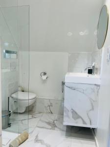 Baño blanco con aseo y lavamanos en Superbe appartement avec jardin et parking privé, en Ris-Orangis