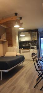 a bedroom with a bed and a chair and a kitchen at SALTILLO ALTO WHITE STUDIO in Torremolinos