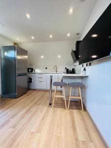 een keuken met een roestvrijstalen koelkast en 2 krukken bij Superbe appartement avec jardin et parking privé in Ris-Orangis