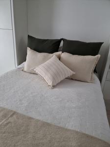 Una cama con cuatro almohadas encima. en Un departamento de lujo en La Perla en Mar del Plata