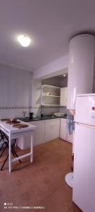 een witte keuken met een tafel en een koelkast bij Big and cozy apartment with a big terrace in the center of the old town with AC from 2024 summer season in Marbella