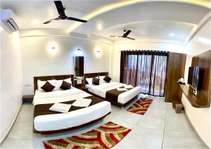 a hotel room with two beds and a television at Shivsagar Agro Tourism, Tapola in Mahabaleshwar