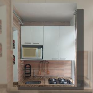 a kitchen with a sink and a microwave at Apartamento com piscina, apenas 200 metros do mar in Capão da Canoa