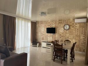 villa with beautiful view 4 في تبليسي: غرفة معيشة مع طاولة وساعة على الحائط