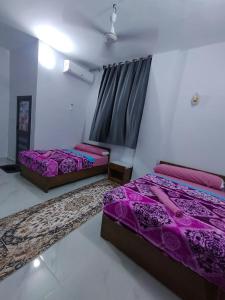 Onaty Narty Guest house في أسوان: سريرين في غرفة ذات أغطية أرجوانية