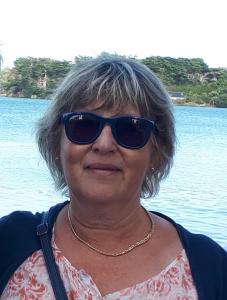 a woman wearing sunglasses standing in front of the water at chambres chez l habitant in Saint-Sauveur