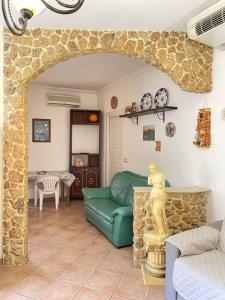 sala de estar con sofá verde y pared de piedra en Appartamento Garibaldi centro Sicilia., en Barrafranca