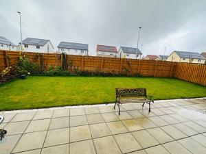 een parkbank in een achtertuin met een hek bij Modern new build detached House near Edinburgh Airport in East Calder
