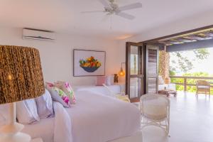 a white bedroom with a bed and a balcony at Hotel Agua Baru by Mustique in Barú