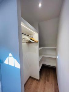Superbe appartement avec jardin et parking privé في Ris-Orangis: خزانة ملابس مع جدران بيضاء وأرضيات خشبية