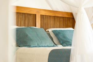 a bed with blue pillows and a canopy at Casa Mandala Corumbau in Corumbau