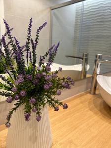 un vaso pieno di fiori viola su un bancone in bagno di Puertito Beach Suites 1 a Puertito de Güímar
