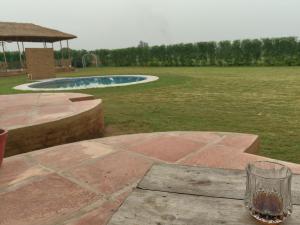 a glass of wine sitting on a table next to a pool at TENTFORTABLE Village Retreat in Agra