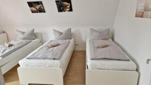two beds in a room with white sheets and pillows at 2,5 Zimmerwohnung in Mönchengladbach