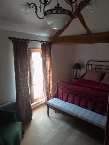 um quarto com uma cama vermelha e uma janela em la tour du fauconnier em Doué-la-Fontaine