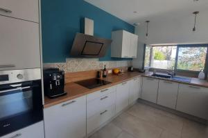 a kitchen with white cabinets and a blue wall at Beaujolais - Maison pierres dorées in Ville-sur-Jarnioux