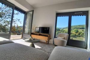 a living room with a tv and large windows at Beaujolais - Maison pierres dorées in Ville-sur-Jarnioux