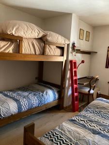 Un dormitorio con dos literas y una mesa. en NIGRITELLA, en Madonna di Campiglio