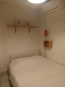 - une chambre avec un lit blanc et une étagère dans l'établissement Villa Anna, à Sérignan-du-Comtat