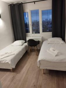 two beds in a room with a desk and window at F3 au bord de la Marne, à deux pas de Paris +Box ! in Maisons-Alfort
